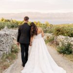 The blue Adriatic sparkles behind the couple on the field.